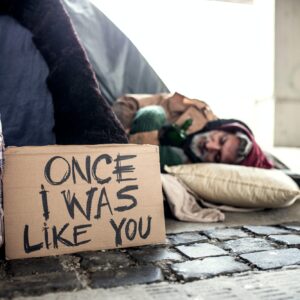 Homeless beggar man lying on the ground outdoors in city, sleeping.